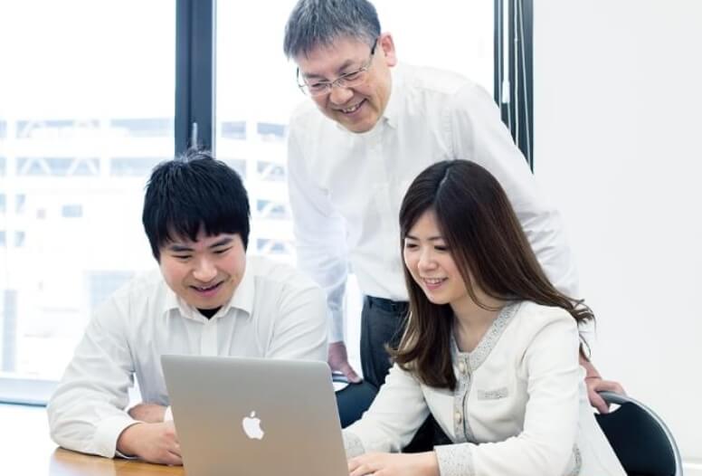 チームでノートパソコンに向かって企画を考えている写真